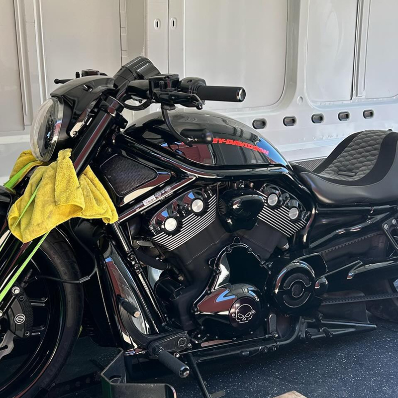 Black cruiser motorcycle with red tank lettering strapped inside a van