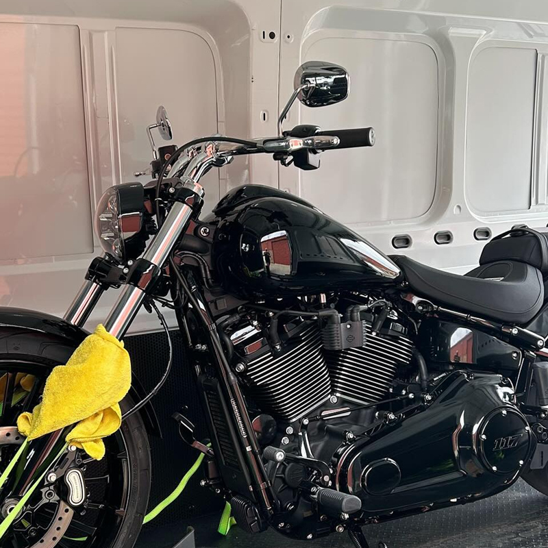 Black cruiser motorcycle with a yellow cloth on the fork inside a van